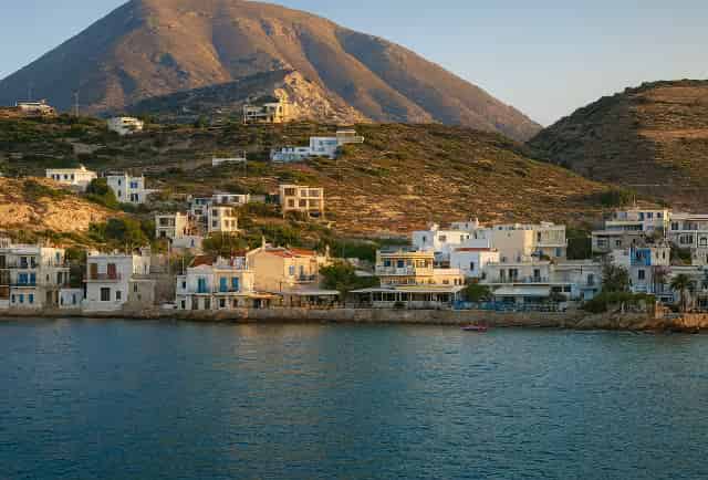 Παραδοσιακά λευκά και γαλάζια κτίρια του ήσυχου ψαροχωριού Μόχλος στην Ανατολική Κρήτη, με φόντο απότομο άνυδρο βουνό