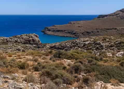 Εντυπωσιακό άνυδρο τοπίο και ψηλοί γκρεμοί πάνω από απομακρυσμένο γαλάζιο κόλπο κοντά στη Ζάκρο, Ανατολική Κρήτη
