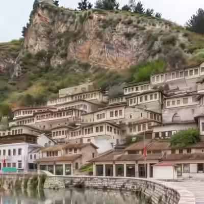 Case otomane tradiționale albe etajate pe deal deasupra râului, în centrul istoric al orașului Berat, Albania.