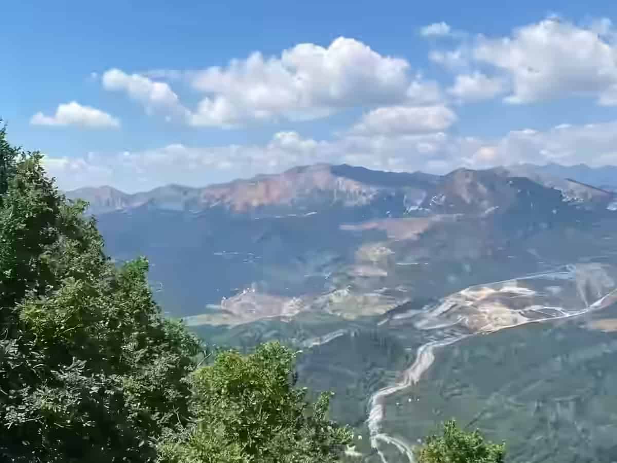 Priveliște de pe Muntele Dajti spre o vale verde și o carieră de piatră, peste peisajul din afara orașului Tirana, Albania, sub un cer albastru.