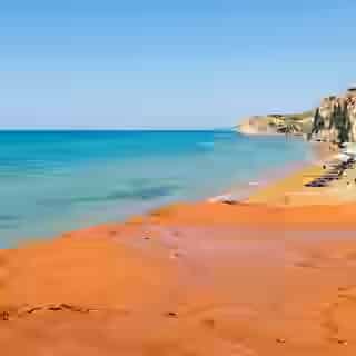 Spiaggia Xi a Cefalonia con il caratteristico fondale di argilla rosso-arancio e Mar Ionio turchese, spiaggia minerale unica in Grecia