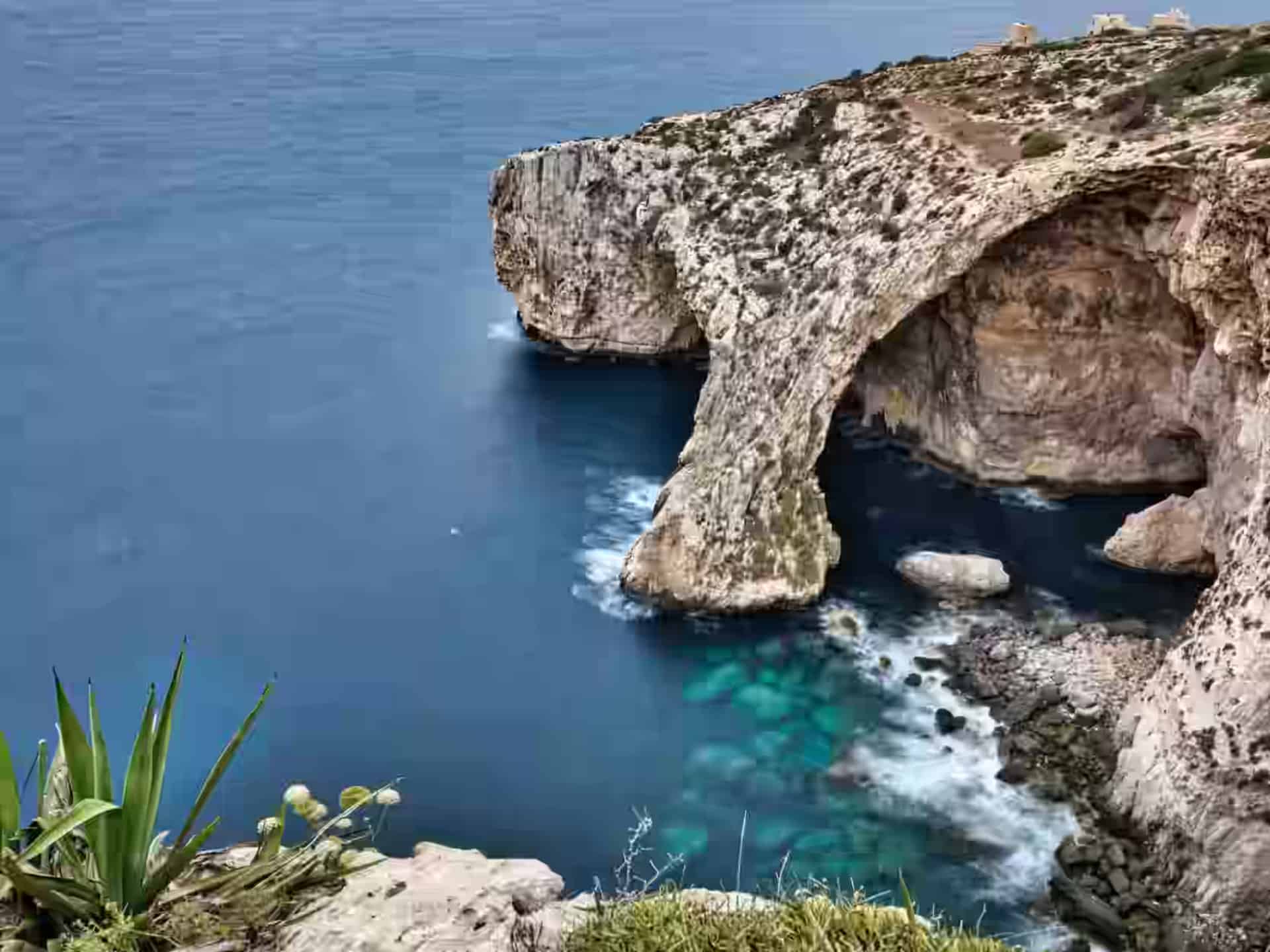 Der Kalksteinbogen der Blauen Grotte bei Wied iż-Żurrieq, Malta, der unterhalb der Klippen ins tiefblaue Wasser ragt.