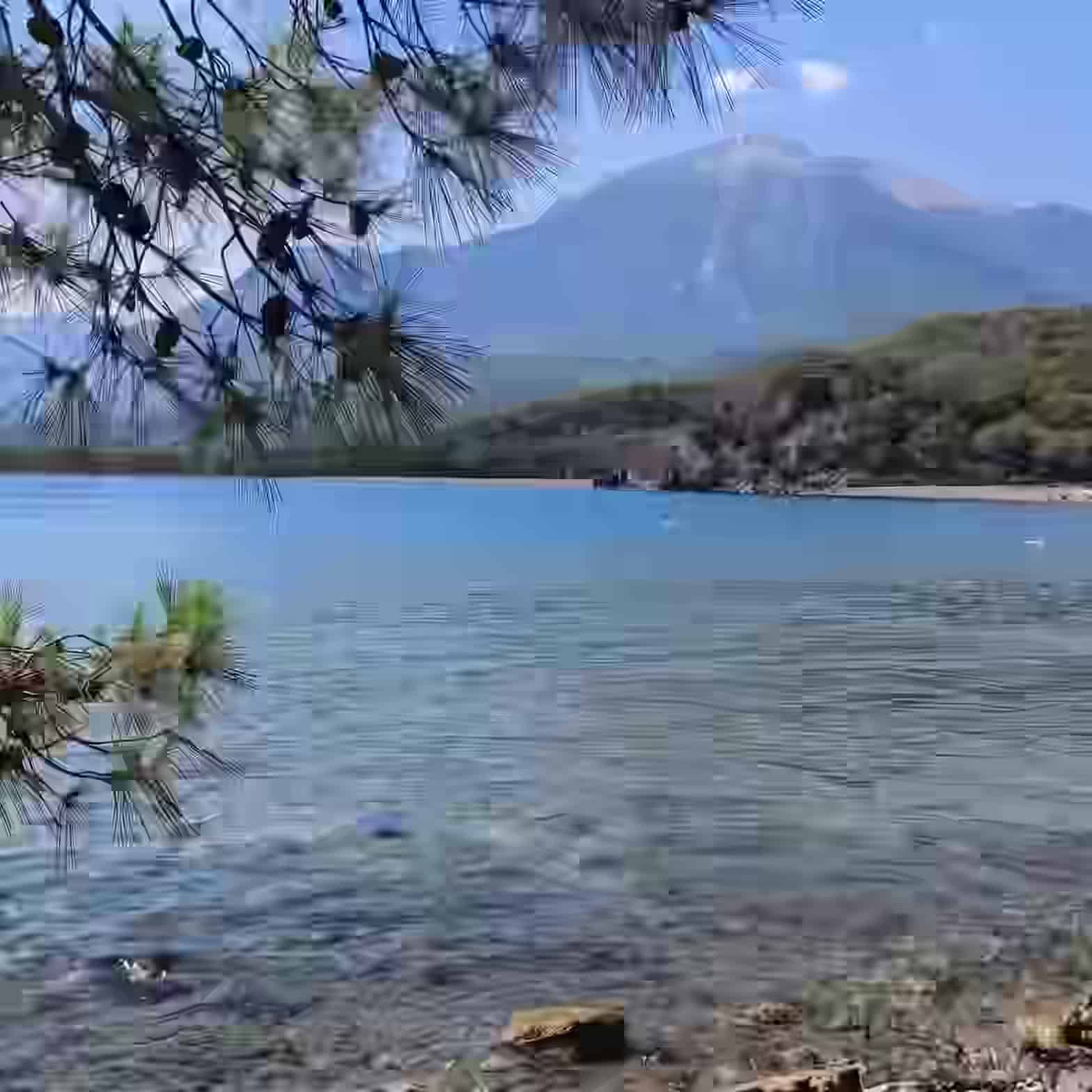 Apa limpede și puțin adâncă a golfului portului antic de la Phaselis, lângă Antalya, Turcia, încadrată de pini și munți.