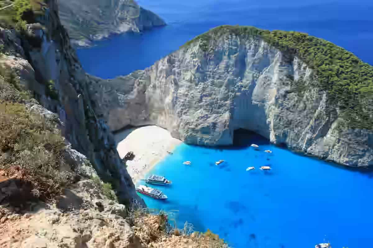 Widok z lotu ptaka na plażę Navagio na Zakynthos z zardzewiałym wrakkiem statku na białym piasku otoczonym białymi wapiennymi klifami i turkusowym Morzem Jońskim