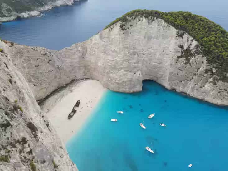 Punkt widokowy na klifie nad plażą Navagio na Zakynthos z białymi wapiennymi skałami i zardzewiałym wrakiem statku głęboko poniżej