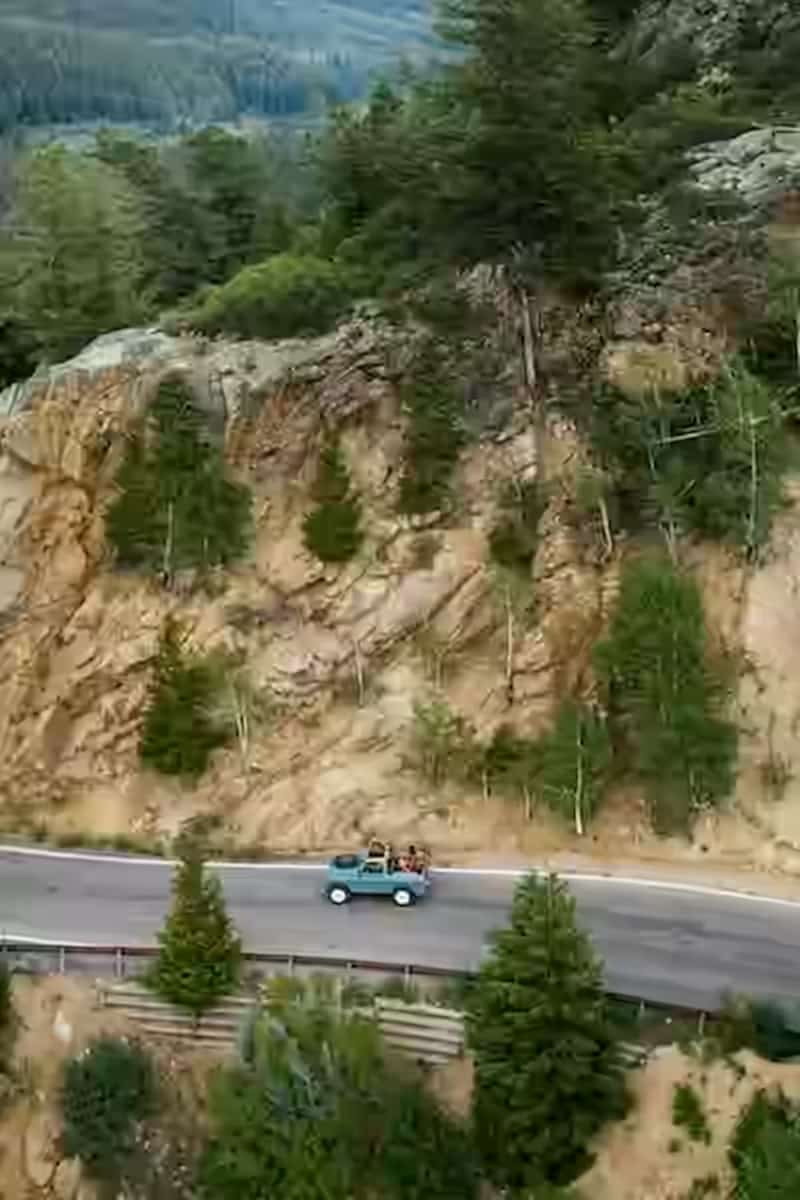 Car traveling on a winding mountain road under a clear blue sky