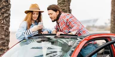 Customers reviewing the details and confirming no hidden fees on their car rental booking confirmation via a mobile phone.