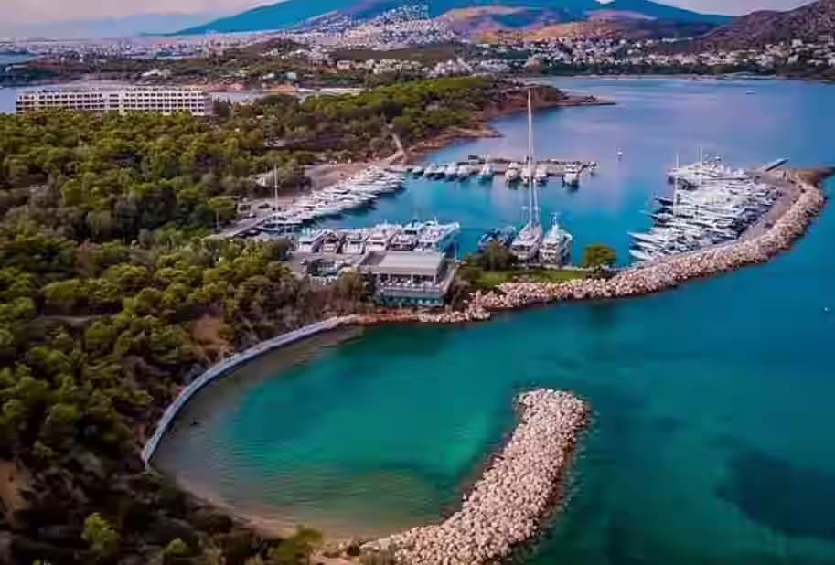 Widok z lotu ptaka na luksusową marinę Vouliagmeni i zielony półwysep Astir na Riwierze Ateńskiej.