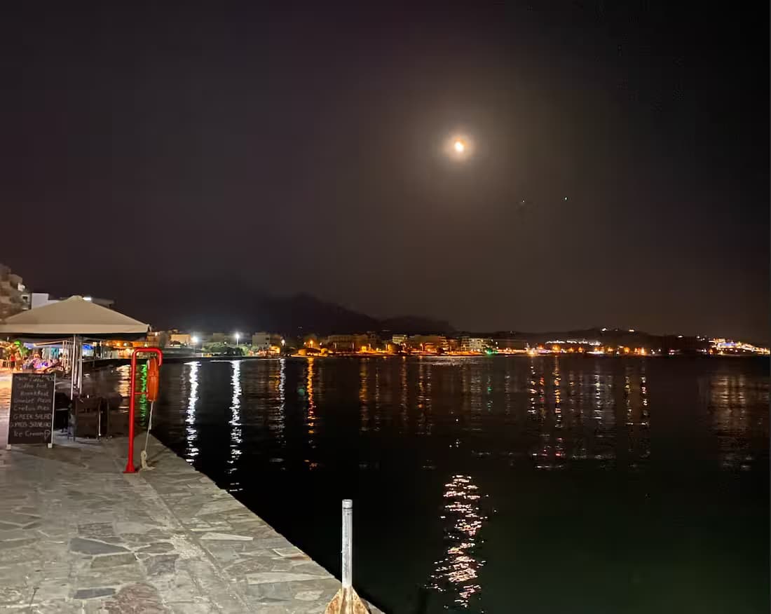 Φωτισμένη παραλιακή περατζάδα και λιμάνι της Ιεράπετρας, Νότια Κρήτη, με τα φώτα της πόλης να καθρεφτίζονται στη γαλήνια θάλασσα τη νύχτα