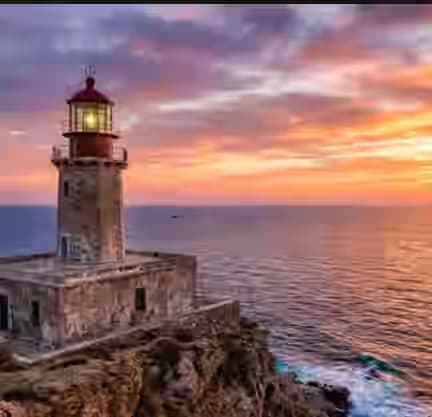 Lo storico Faro di Armenistis su una scogliera a Mykonos durante un colorato tramonto sull'Egeo