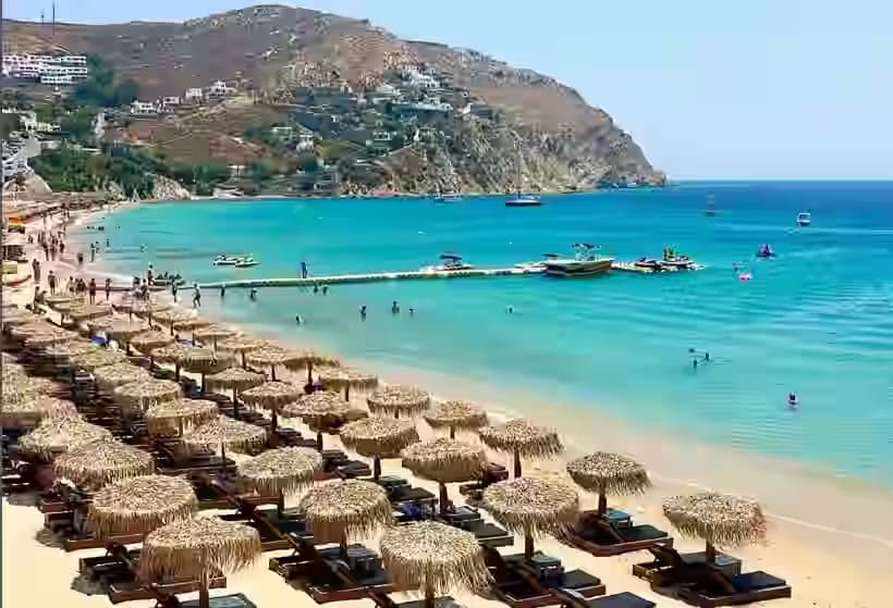 File di ombrelloni di paglia sulla bellissima spiaggia sabbiosa di Elia Beach a Mykonos