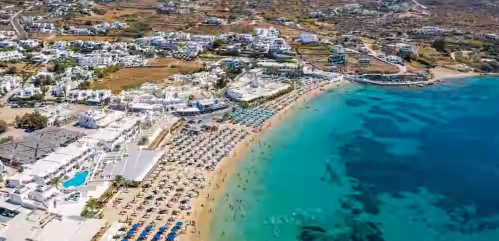 Εναέρια άποψη της οργανωμένης αμμώδους παραλίας Ορνός με γαλάζια νερά στη Μύκονο