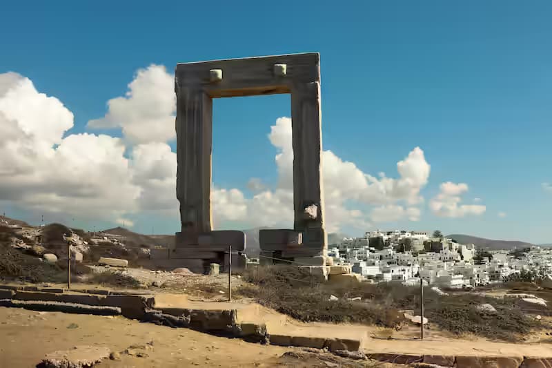 The Portara marble gate of the unfinished Temple of Apollo silhouetted against a vivid orange sunset over the Aegean Sea, Naxos, Greece