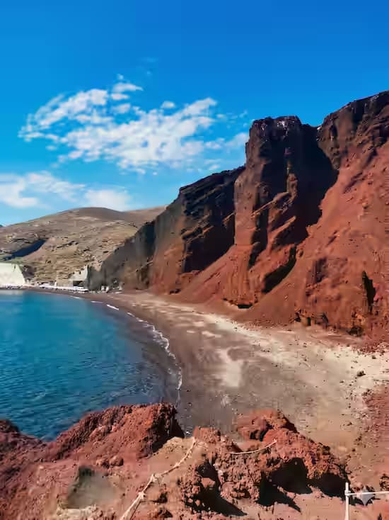 Red Beach on Santorini with towering red volcanic cliffs, dark pebbles and crystal-clear turquoise Aegean water
