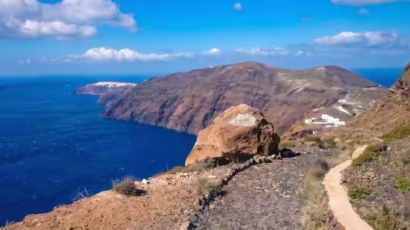 White cubic houses and iconic blue-domed churches of Oia perched on Santorini's caldera cliff edge at golden hour