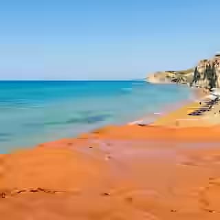 Plage de Xi à Céphalonie avec son caractéristique rivage d'argile rouge-orangé et la mer Ionienne turquoise, plage minérale unique en Grèce