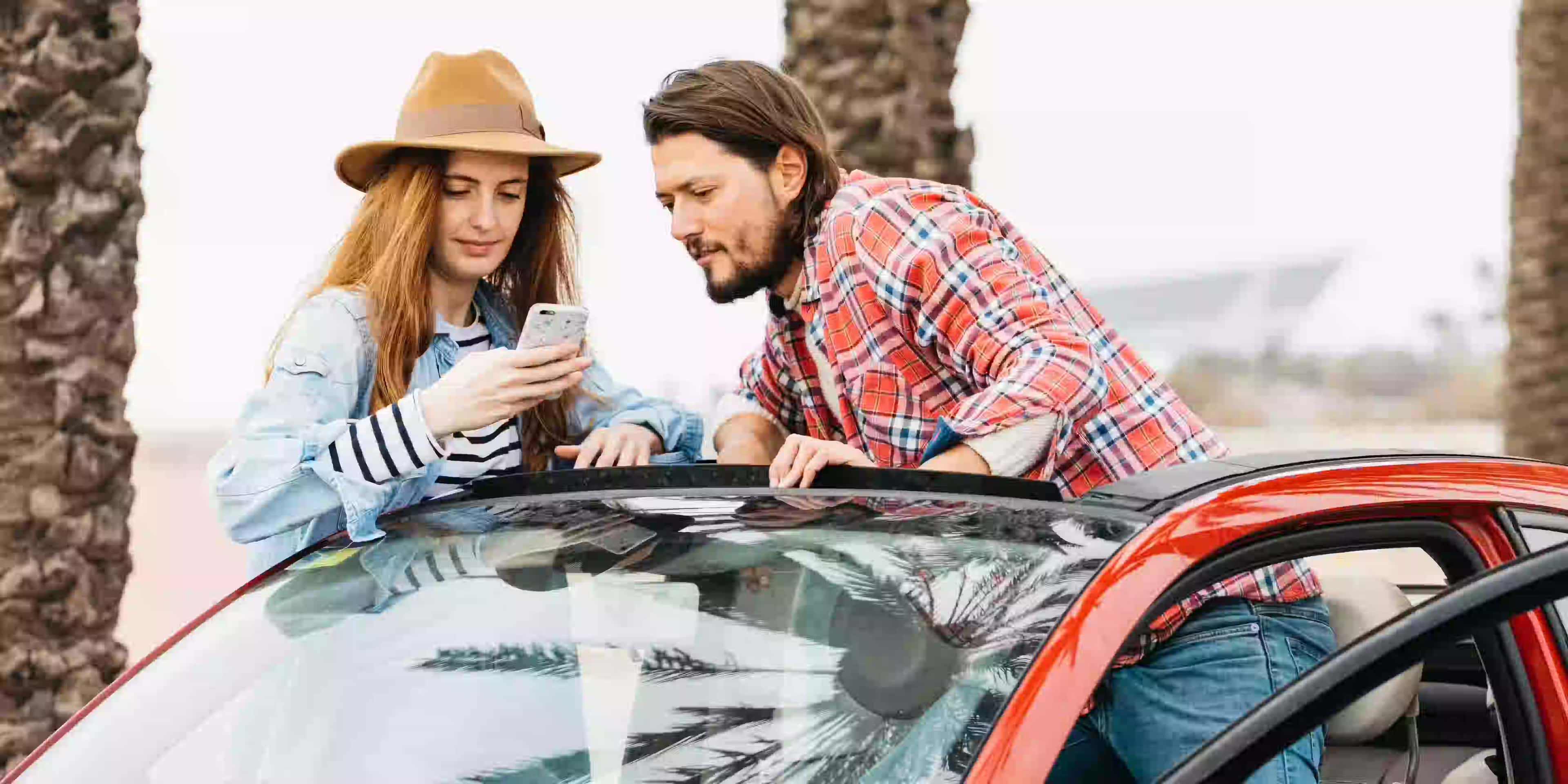 Customers reviewing the details and confirming no hidden fees on their car rental booking confirmation via a mobile phone.