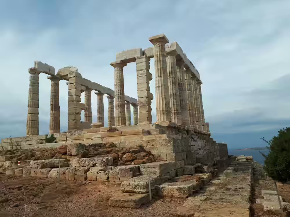 View of the ancient Temple of Poseidon at Cape Sounion overlooking the sea, a popular coastal driving destination in Greece.