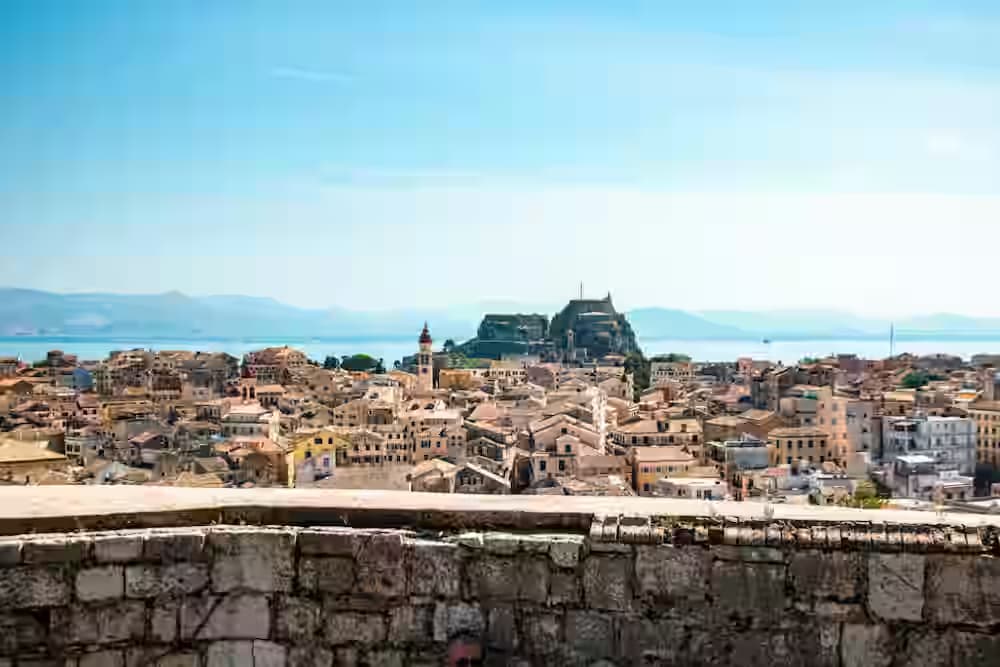 Panoramablick auf die historische Altstadt von Korfu mit orangefarbenen Ziegeldächern und der venezianischen Festung am Ionischen Meer – ein Highlight für Mietwagen-Reisende.