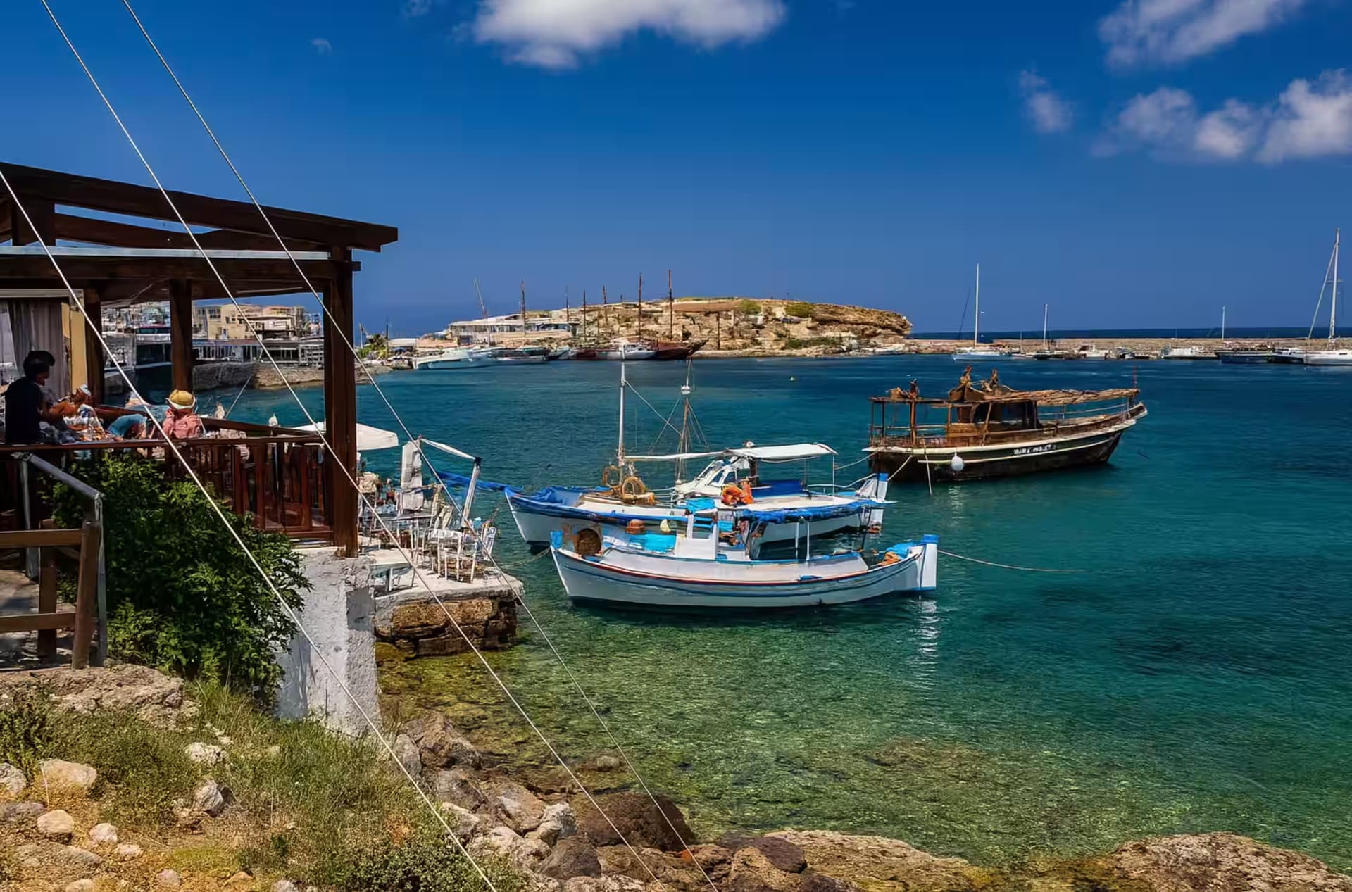 Παραδοσιακά καΐκια και παραθαλάσσιο εστιατόριο στο παλιό λιμάνι Χερσονήσου, Κρήτη, με κρυστάλλινα τιρκουάζ νερά και παραλιακή περατζάδα