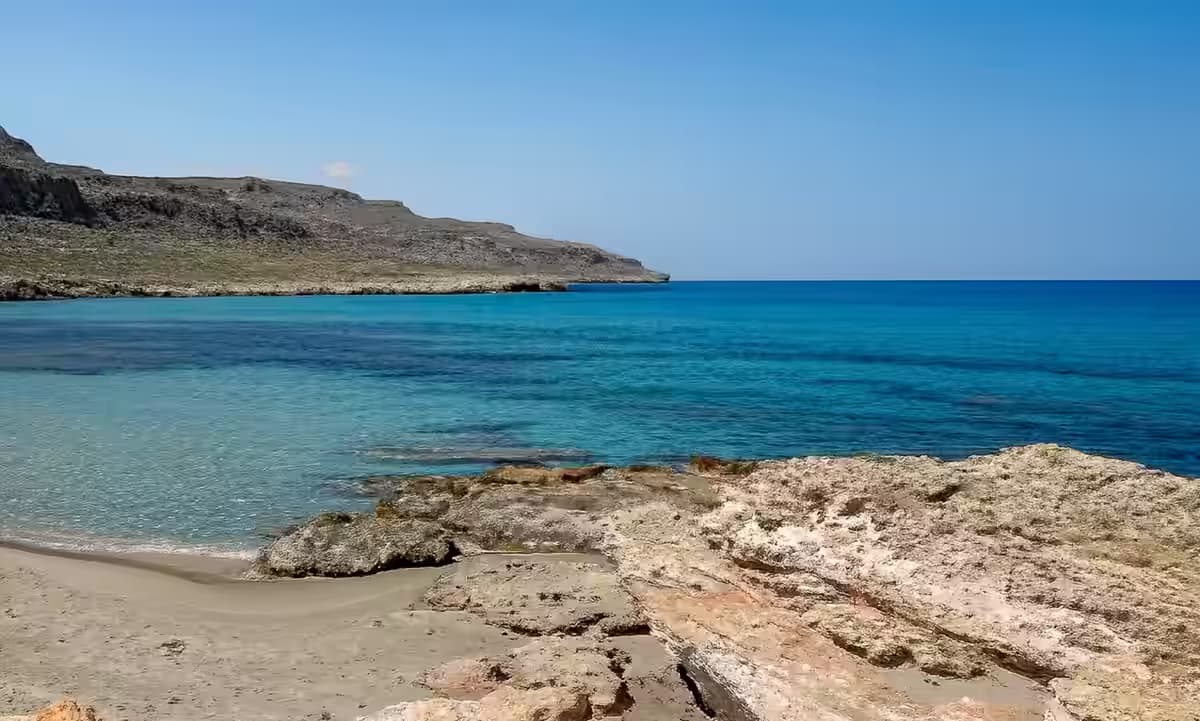 Crystal-clear turquoise water and rugged, arid coastline near Xerokambos, East Crete, highlighting the remote and unspoiled beaches