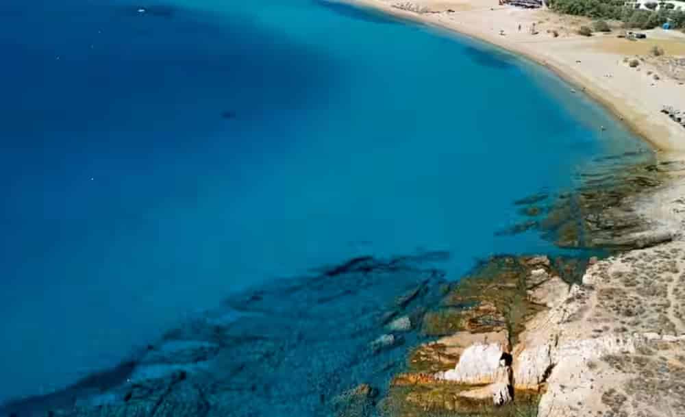 Vista aerea del Golden Beach (Chryssi Akti) a Paros, Grecia, con acque cristalline turchesi e una lunga spiaggia sabbiosa. Pianifica la tua visita facilmente con un noleggio auto Karpadu.