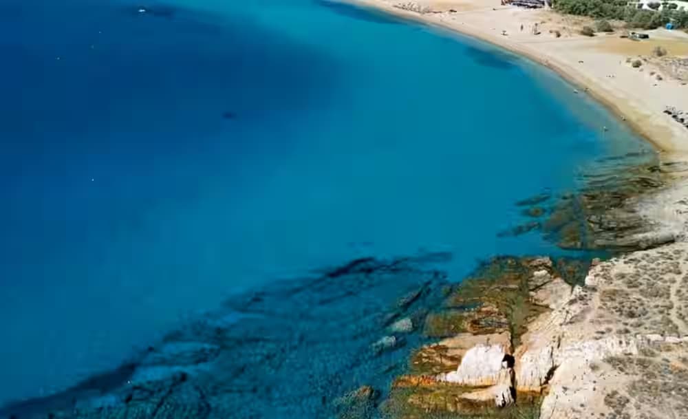 Aerial view of Golden Beach (Chrissi Akti) in Paros, Greece, featuring crystal clear turquoise waters and a long sandy shore. Plan your visit easily with a Karpadu car rental.