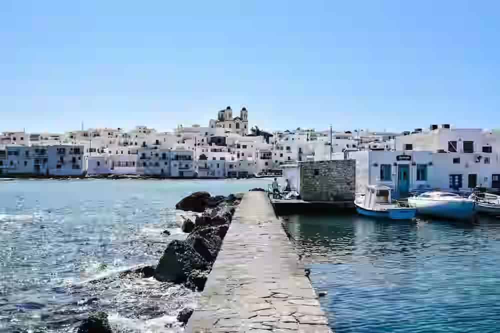 Vista pittoresca del porto del borgo dei pescatori di Naoussa a Paros, Grecia, con le tipiche case bianche cubiche e le barche da pesca. Una sosta imperdibile nel tour dell'isola con un noleggio auto Karpadu.