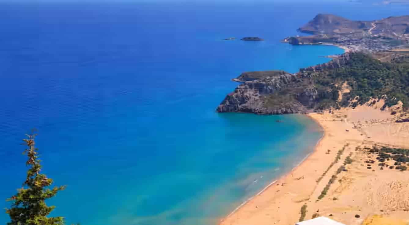 Lotnicza panorama plaży Tsambika na Rodos ze złotym piaskiem i turkusową wodą – top destynacja z wynajętym samochodem Karpadu.
