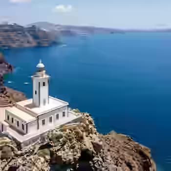 Biała latarnia Akrotiri na południowo-zachodnim cyplu Santorini z panoramicznym widokiem na wejście do kaldery i Morze Egejskie