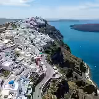 Widok z lotu ptaka na drogę wzdłuż krawędzi kaldery z Fira do Oia na Santorini z białymi domami na klifie i kraterem wulkanicznym poniżej