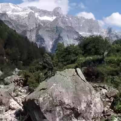 Un bolovan mare într-o vale verde, sub crestele abrupte ale Munților Blestemați din Theth, Albania.