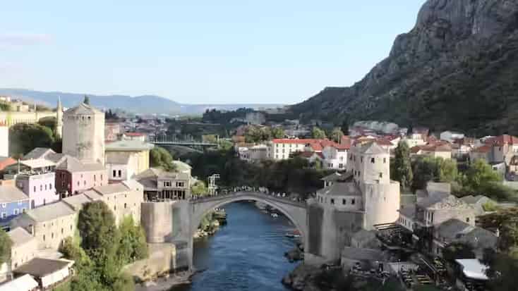 Istorijski lučni kameni most preko reke između starih kamenih zdanja u Mostaru, Bosna i Hercegovina.