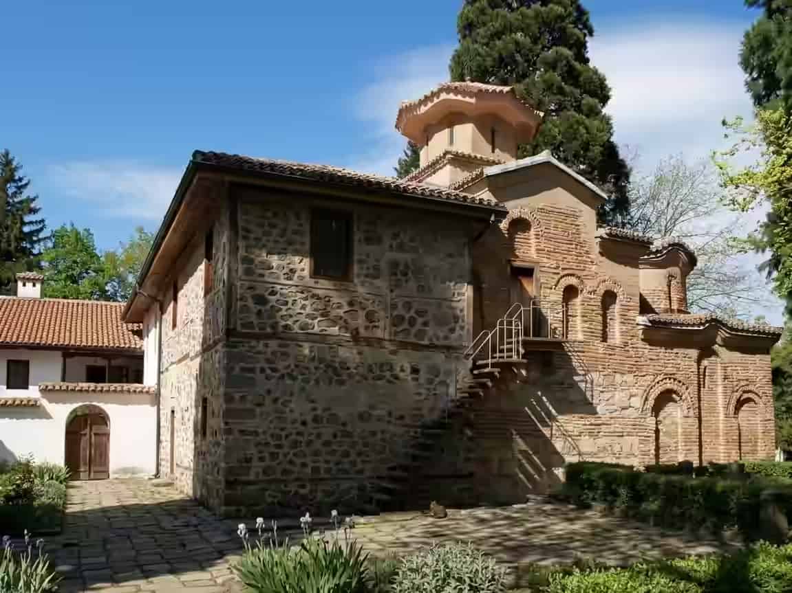 Die historische Fassade aus Ziegel und Stein der Kirche von Bojana zwischen grünen Bäumen in Sofia, Bulgarien.