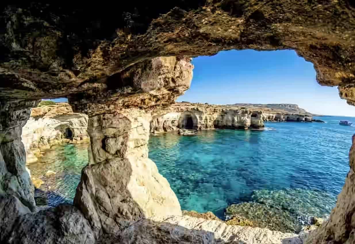 Vedere din interiorul unei peșteri marine stâncoase spre apele albastre și limpezi ale Mediteranei la Capul Greco, Cipru.