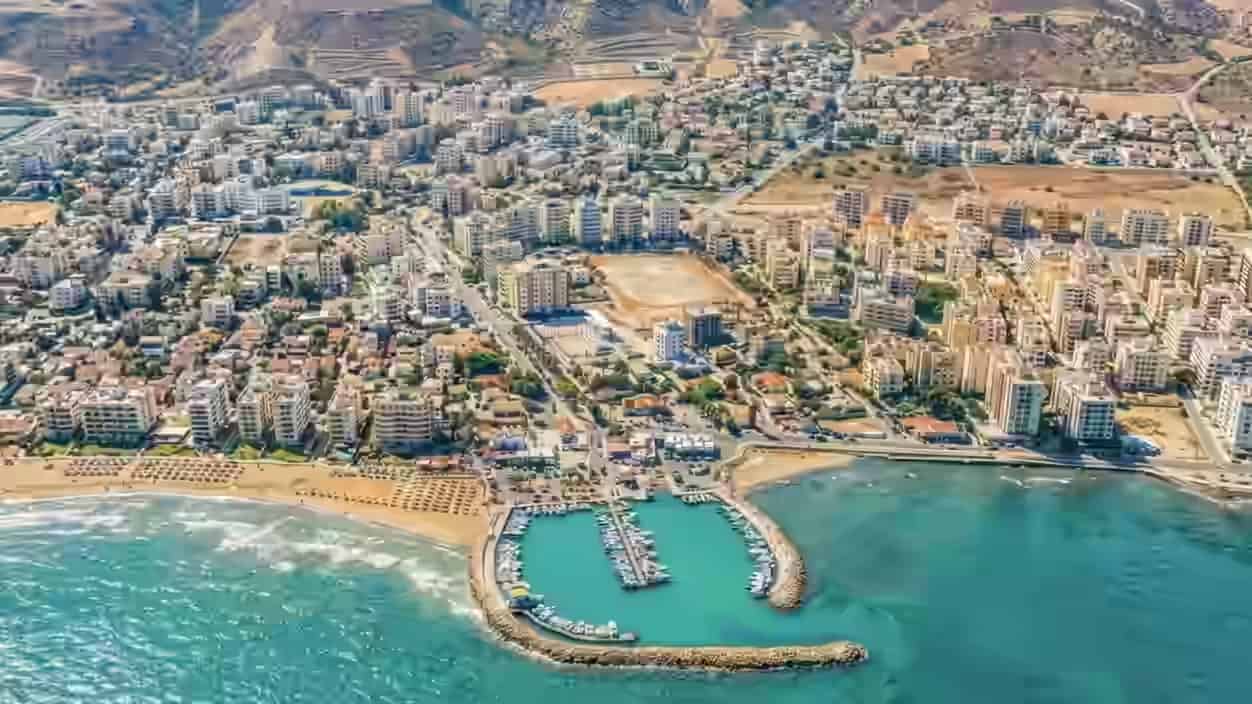 Luchtfoto van de kuststad Larnaca, Cyprus, met de halfronde jachthaven, zandstranden en gebouwen.