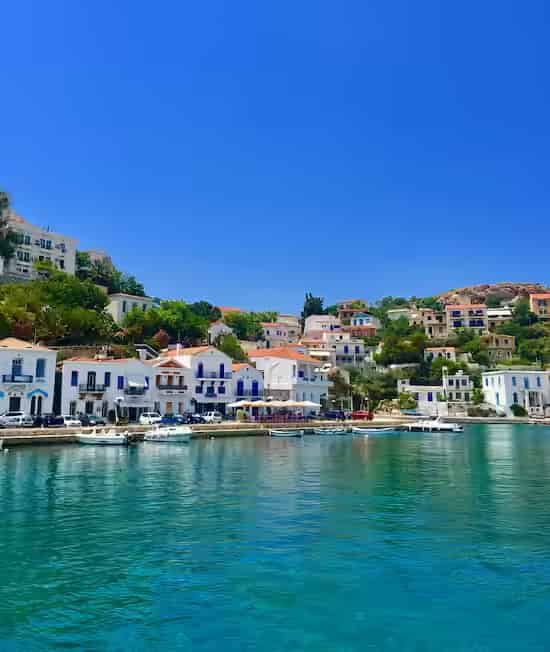 A picturesque view of the harbor in Evdilos, Ikaria, showcasing traditional Greek island architecture and calm sea waters.