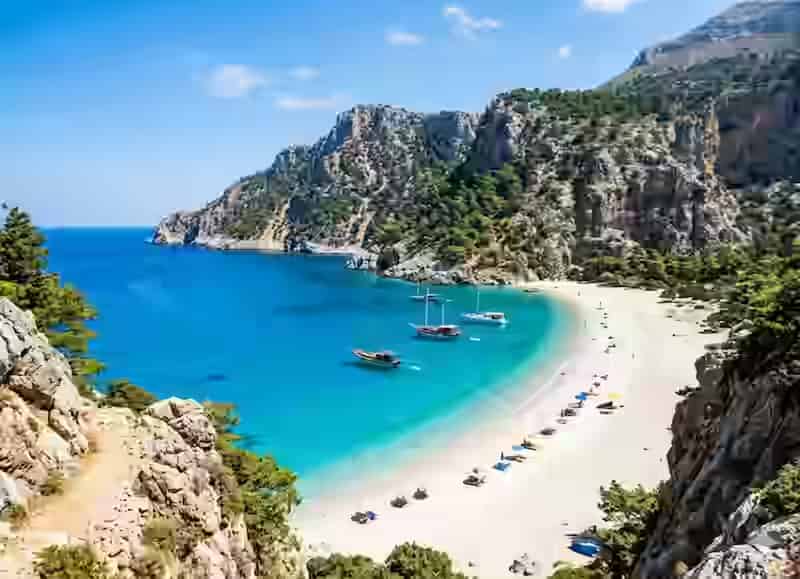 Plage d'Apella à Karpathos avec sable fin blanc, montagnes calcaires abruptes et eau bleue électrique de la mer Égée, l'une des plus belles plages de Grèce