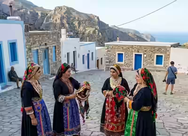 Kobiety z Olympos na Karpathos w ręcznie haftowanych strojach ludowych i nakryciach głowy na brukowanym placu wioski, Dodekanez, Grecja