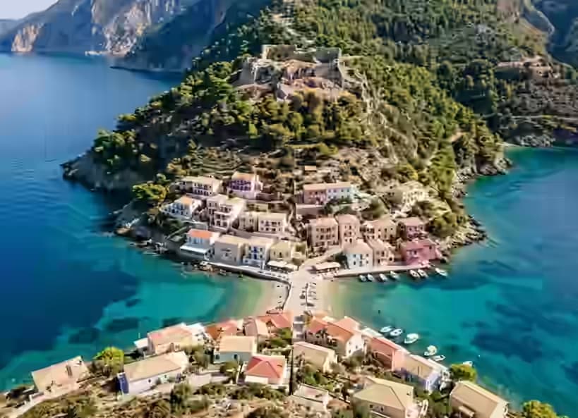 Villaggio di Assos su Cefalonia con case pastello su un istmo stretto e rovine del castello veneziano sulla penisola coperta di pini sopra