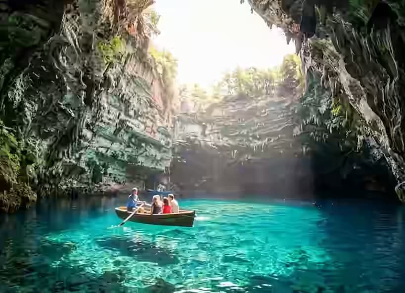 Barca sul lago sotterraneo turchese di Melissani con la luce solare che attraversa l'apertura nel soffitto della grotta collassata, Sami, Cefalonia, Grecia