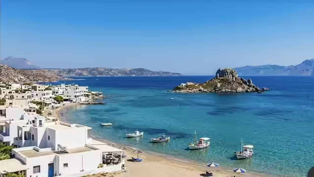 Το λιμάνι της πόλης της Κω με φοίνικες, παραδοσιακά καΐκια και το Κάστρο των Ιπποτών – ιδανικό για εξερεύνηση του νησιού με ένα αυτοκίνητο της Karpadu.