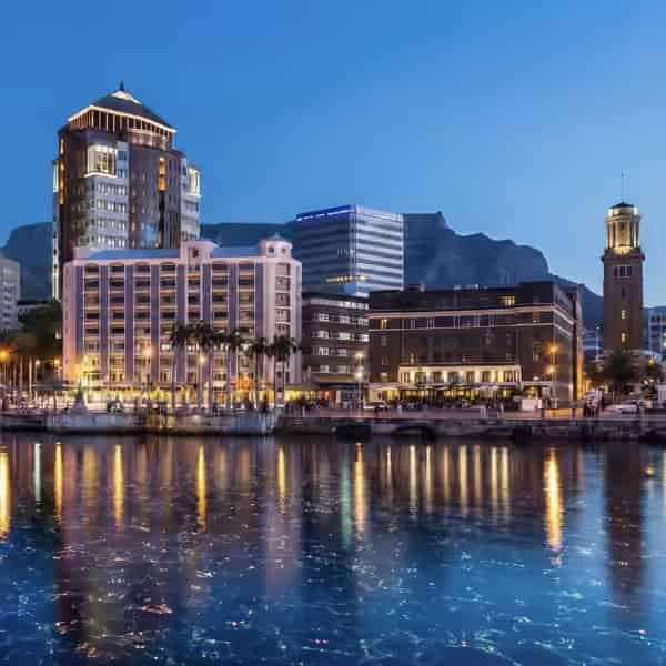 Die beleuchtete Skyline und die Lichter von Port Louis spiegeln sich nachts im Hafen.