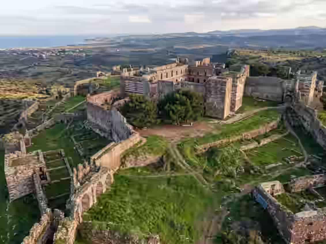 Vue aérienne des vastes ruines du Château de Mytilène, révélant d'anciennes murailles défensives en pierre et de verdoyantes cours herbeuses surplombant les collines ondulantes et la mer au loin, à Lesbos, Grèce.