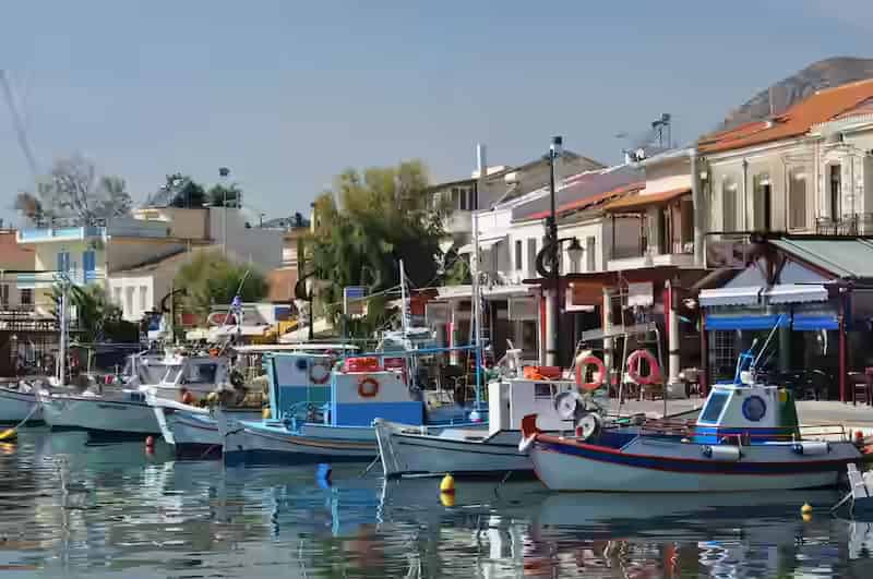A scenic view of the picturesque harbor in Pythagorio, Samos, featuring traditional boats at sunset.
