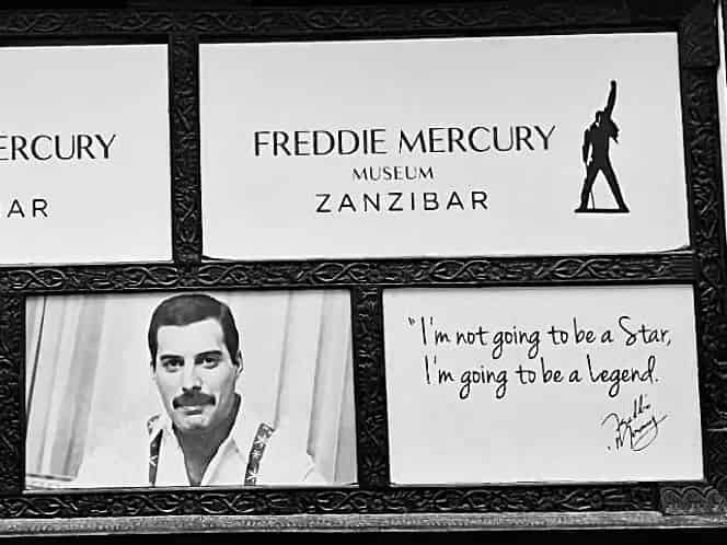 Schwarz-weißes Schild des Freddie-Mercury-Museums in Sansibar, mit einem Porträt des Sängers und einem handschriftlichen Zitat.