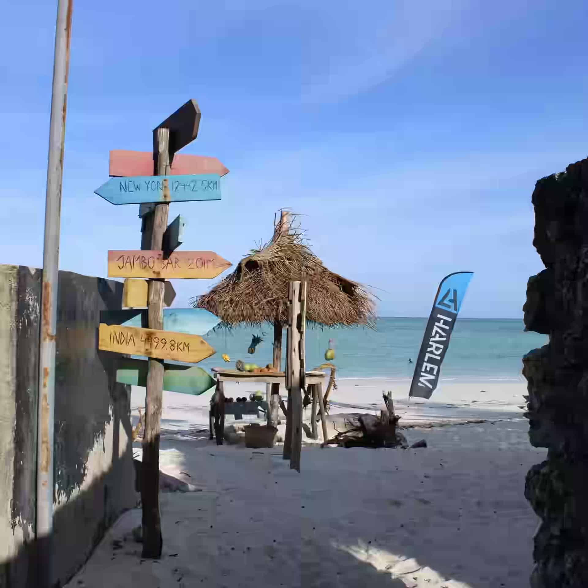 Plajă largă cu nisip alb și ape cristaline puțin adânci la Paje, populară pentru kitesurfing.