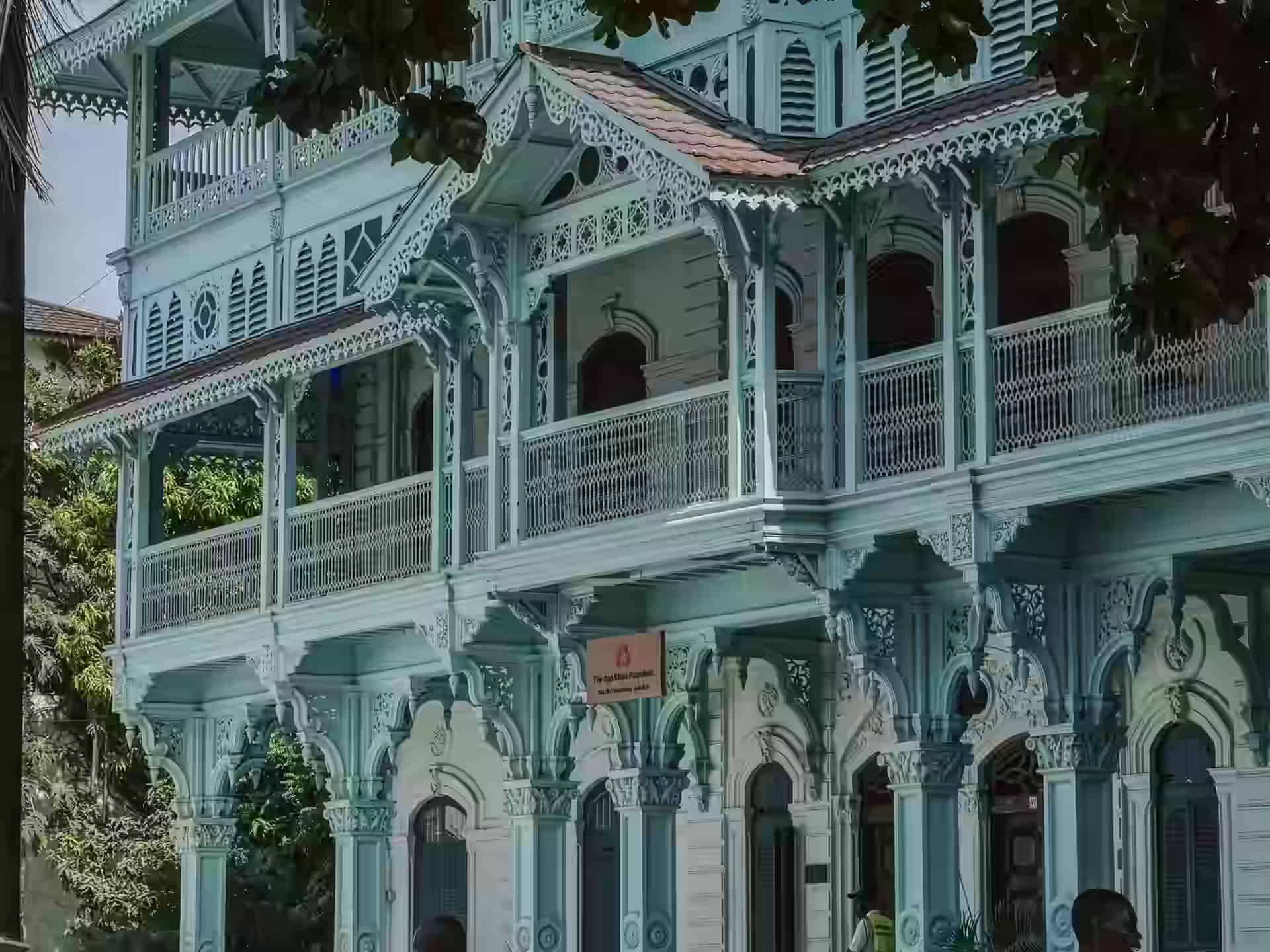 Die blassgrüne Fassade der Old Dispensary in Stone Town, mit geschnitzten Holzbalkonen und Laubsägearbeiten auf jedem Stockwerk.
